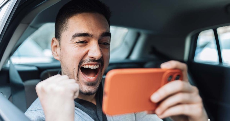 Cheerful man watching a video in his car