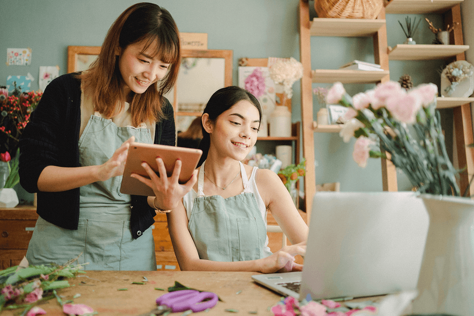 Two women working together holding a tablet and a laptop