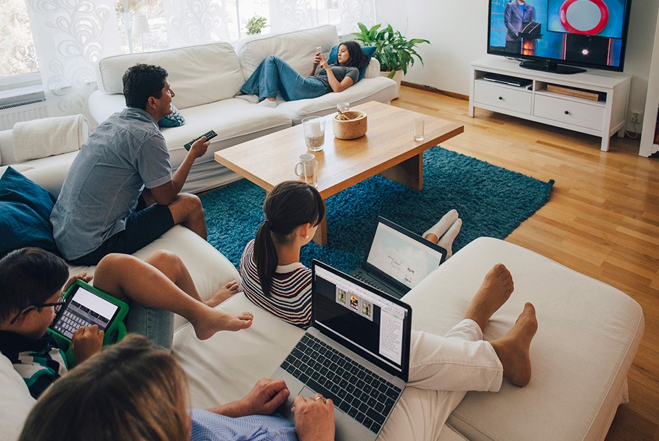 family using various devices in living room