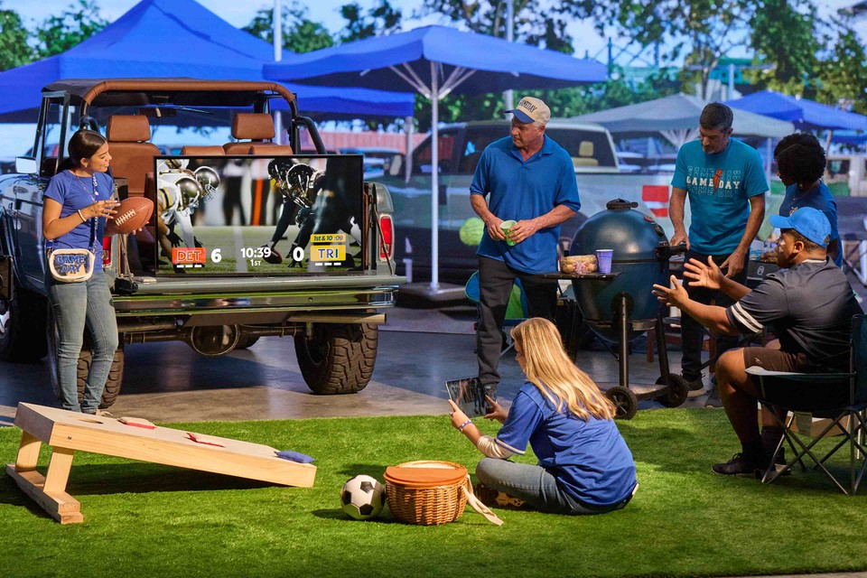 A group of people at a sport's party watching sports on different devices.